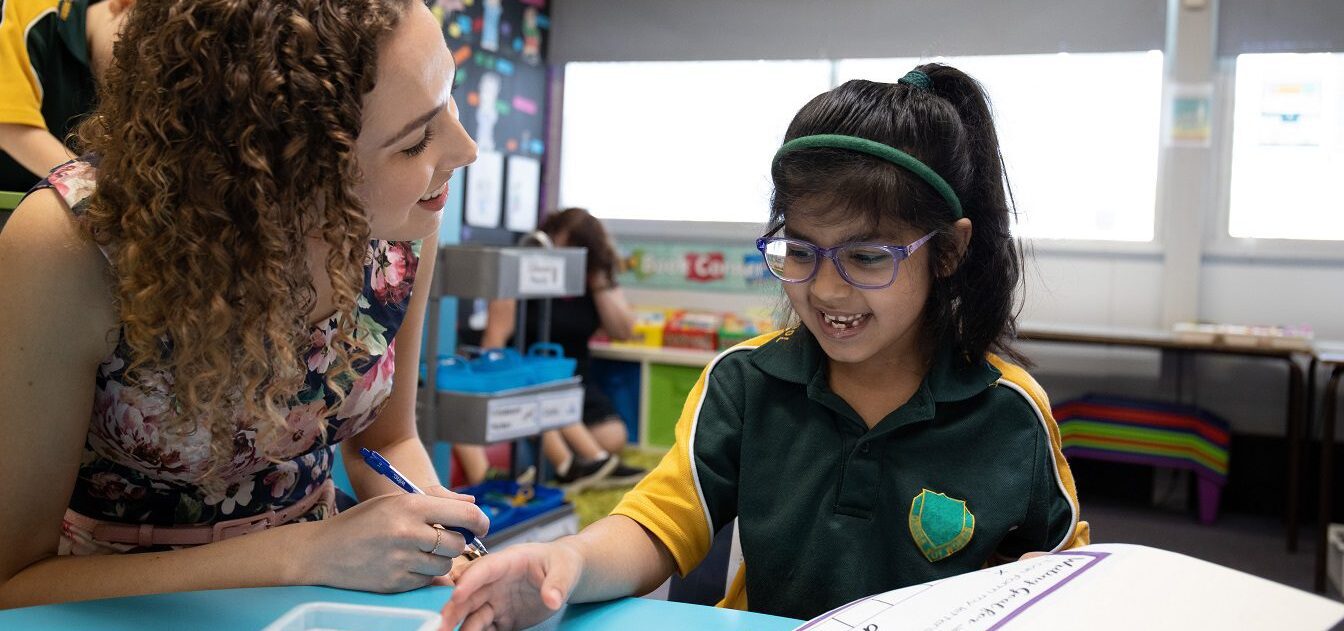 teacher and young student working at a desk