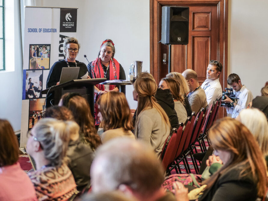 Two women presenting to a crowd.