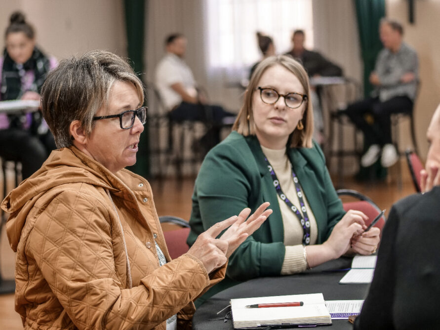 Two women sitting at a table talking.